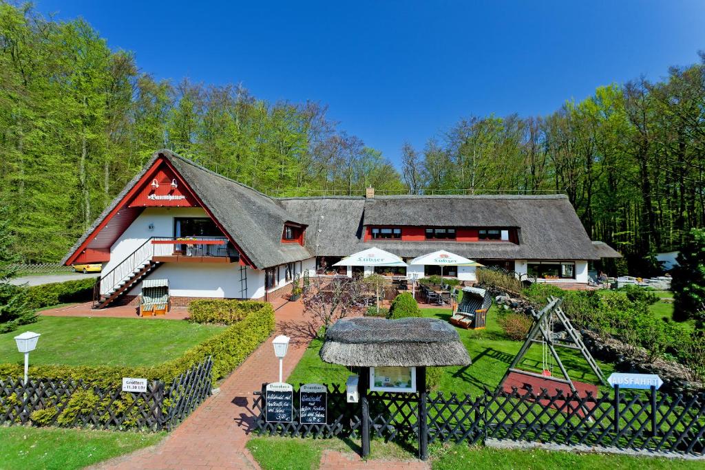 una casa grande con un parque infantil delante de ella en Restaurant & Hotel Baumhaus Hagen, en Sassnitz