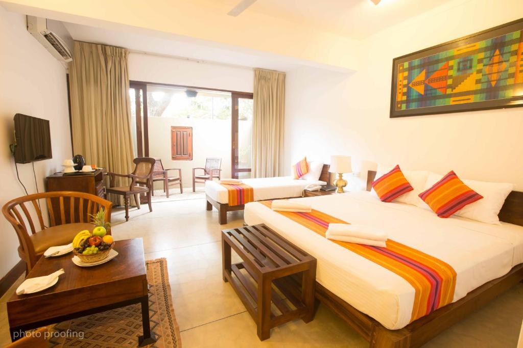 een slaapkamer met 2 bedden en een woonkamer bij Jaffna Heritage Hotel in Jaffna