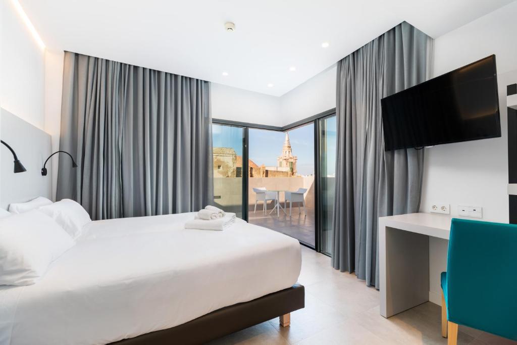 een hotelkamer met een bed, een bureau en een raam bij Dormos Hotel in Cádiz