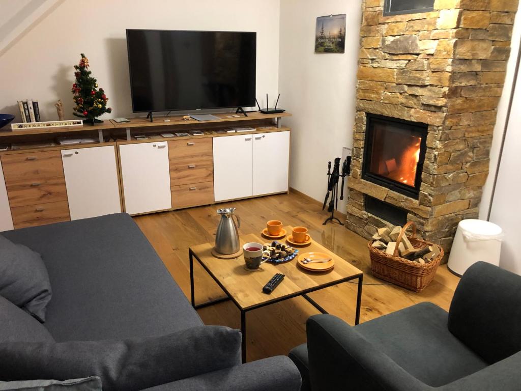 uma sala de estar com um sofá e uma lareira em Apartmán “U nás v podkroví“ v Rezidenci Klostermann, Železná Ruda 24 em Železná Ruda