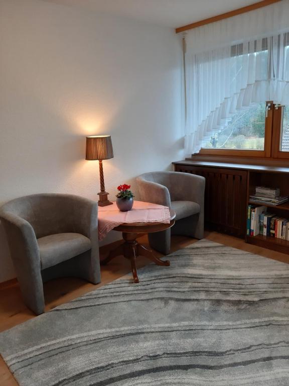 een woonkamer met 2 stoelen en een tafel met een lamp bij Ferienwohnung Viktoria in Lenzkirch