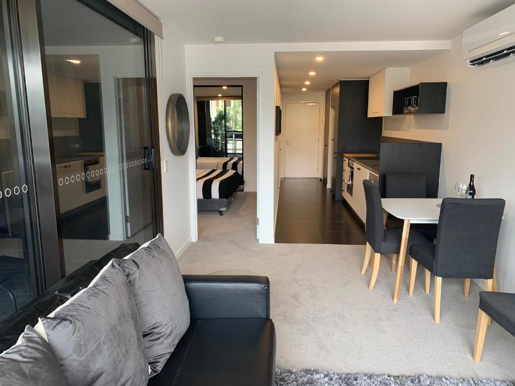 un soggiorno e una cucina con divano e tavolo di Midnight Luxe 1BR 1Bath Apartment 104 in the heart of Braddon Pool Sauna Secure Parking Wine WiFi a Canberra