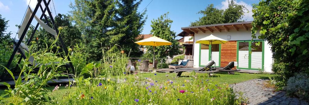 un giardino con due sedie, un tavolo e ombrelloni gialli di BIO Appartement Resort a Bodenmais