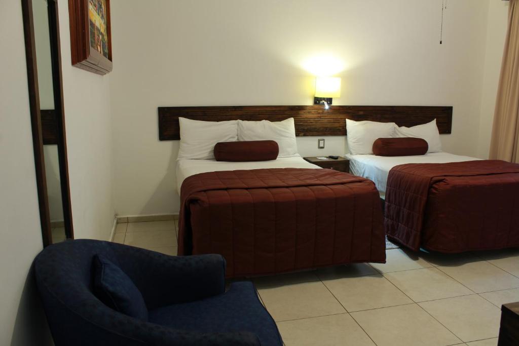 a hotel room with two beds and a chair at HOTEL MI SOLAR EJECUTIVO in Uruapan del Progreso