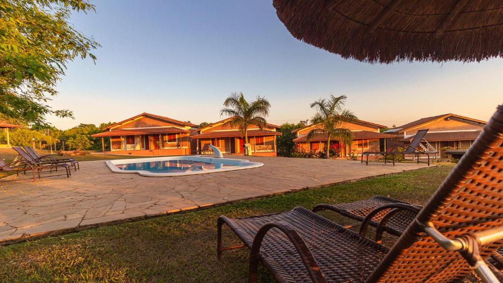 um pátio com cadeiras e uma piscina e casas em Rancho da Cachaça Pousada em Holambra