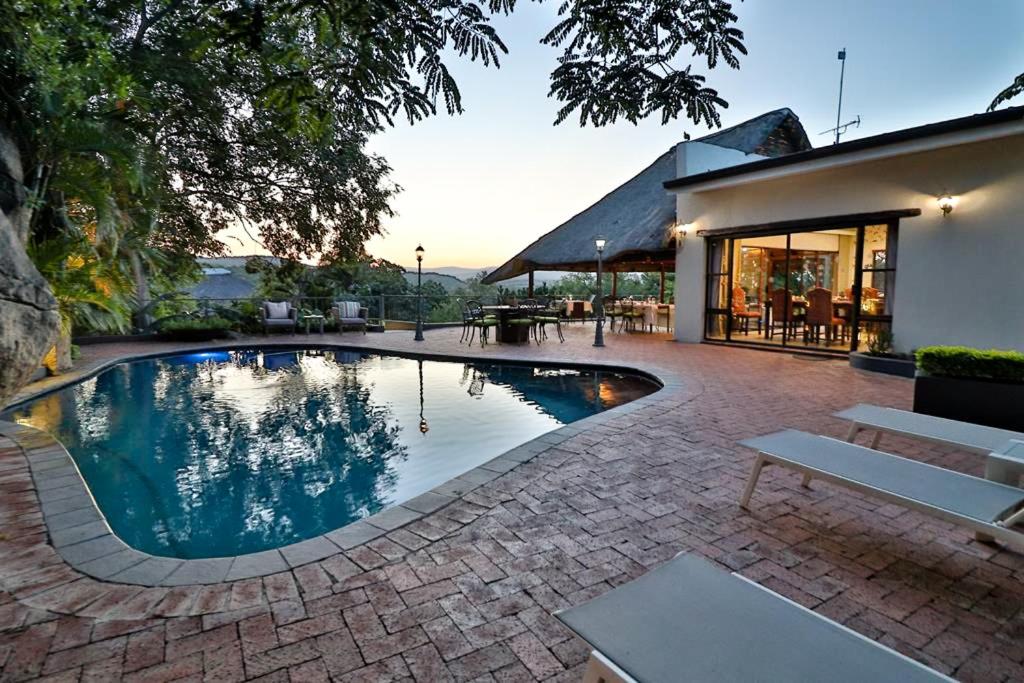 una piscina en un patio con una casa en La Roca Guest House, en Nelspruit