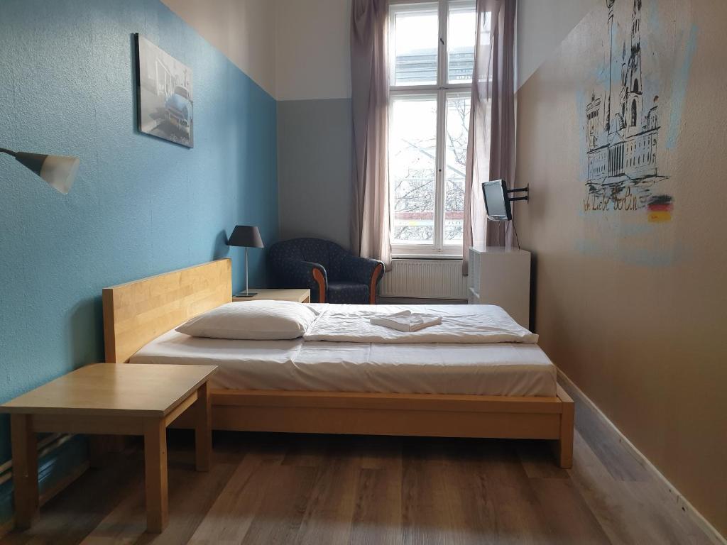 a bedroom with a bed and a table and a window at Pension I in Berlin