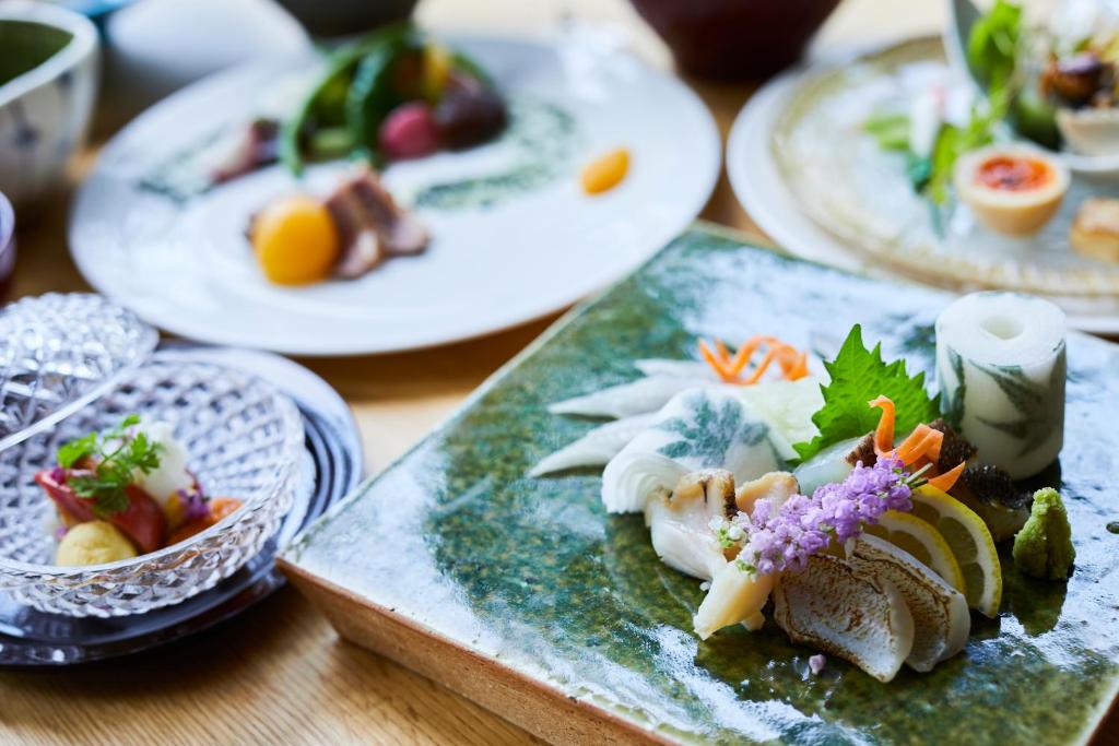 een tafel met borden eten op een tafel bij 宮島離れの宿 IBUKU 別邸 -Miyajima Hanarenoyado IBUKU Bettei- in Ōno