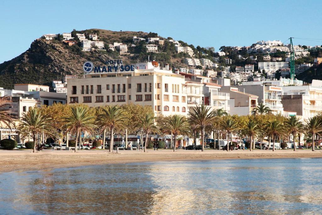 un bâtiment avec des palmiers en face d'une montagne dans l'établissement Prestige Mar y Sol, à Roses