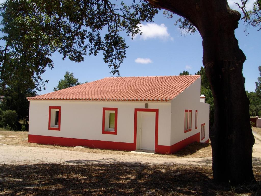 ein kleines weißes und rotes Haus mit einem Baum in der Unterkunft Herdade Rodrigo Afonso in São Teotónio