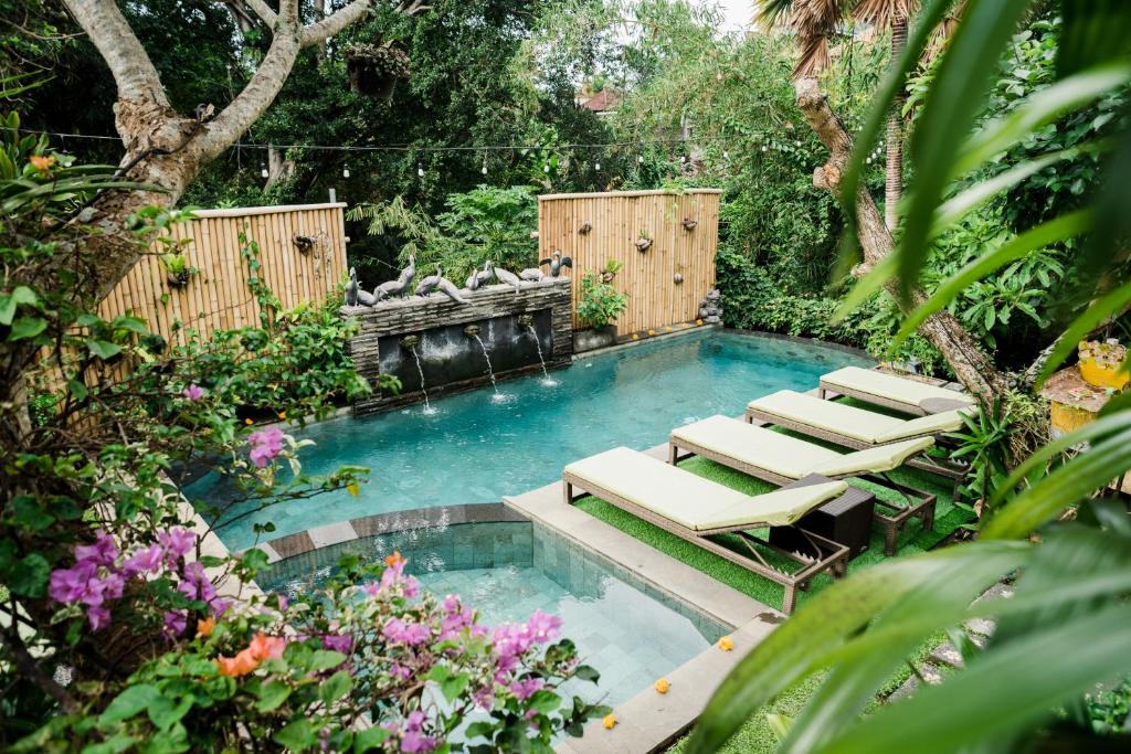 una piscina con sedie a sdraio in giardino di Desak Putu Putra Hidden ad Ubud