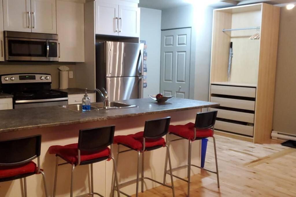 een keuken met een aanrecht met rode stoelen aan een aanrecht bij 1-Bedroom Apartment Bellisimo AG by Amazing Property Rentals in Gatineau