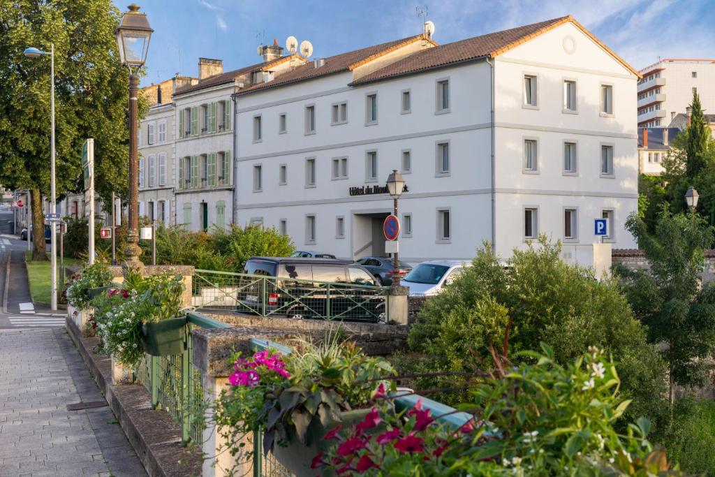 uma rua com um edifício branco e algumas flores em Hôtel du Moulin em Niort