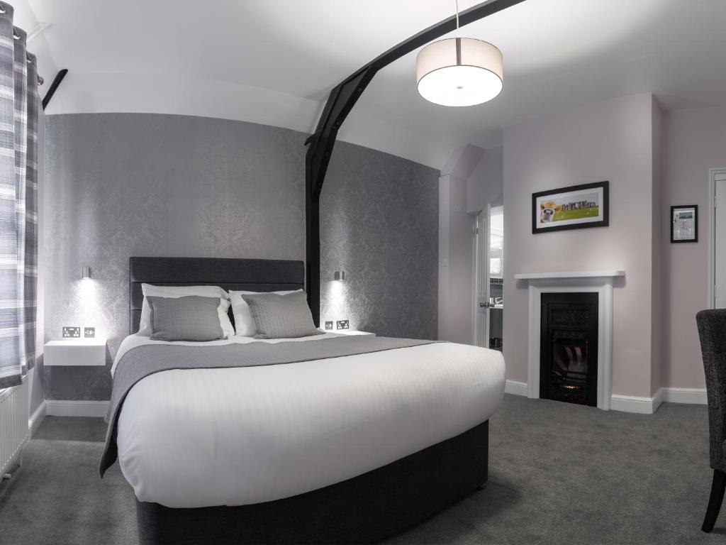 a bedroom with a large white bed and a fireplace at Qudos in Salisbury