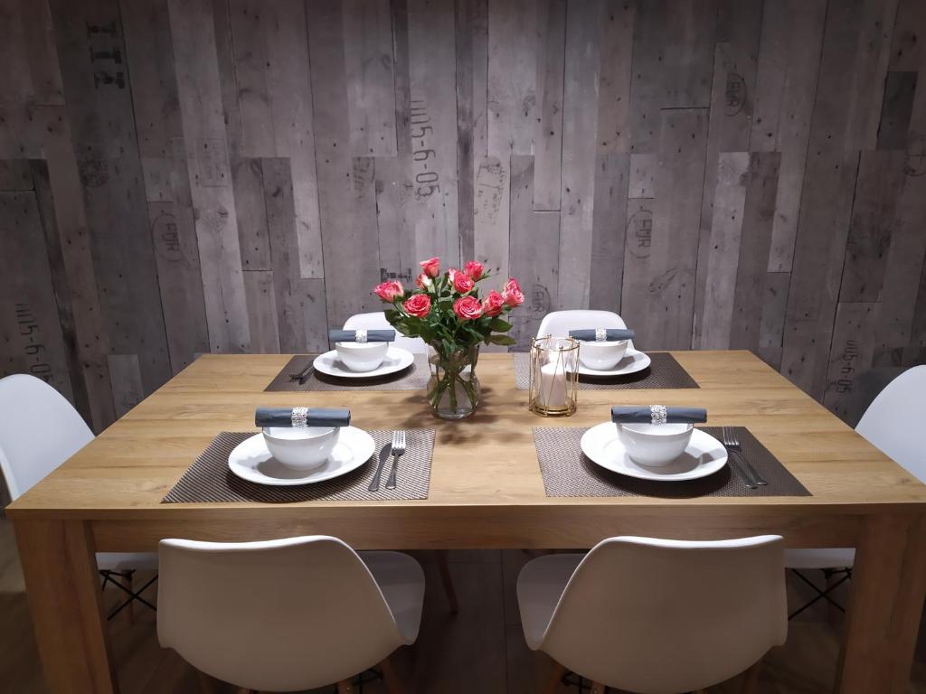 a wooden table with chairs and a vase of flowers at Apartament KAOLA in Jelenia Góra