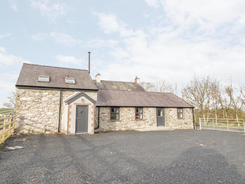 ein Steinhaus mit einer Einfahrt davor in der Unterkunft Rhydau Cottage in Bangor