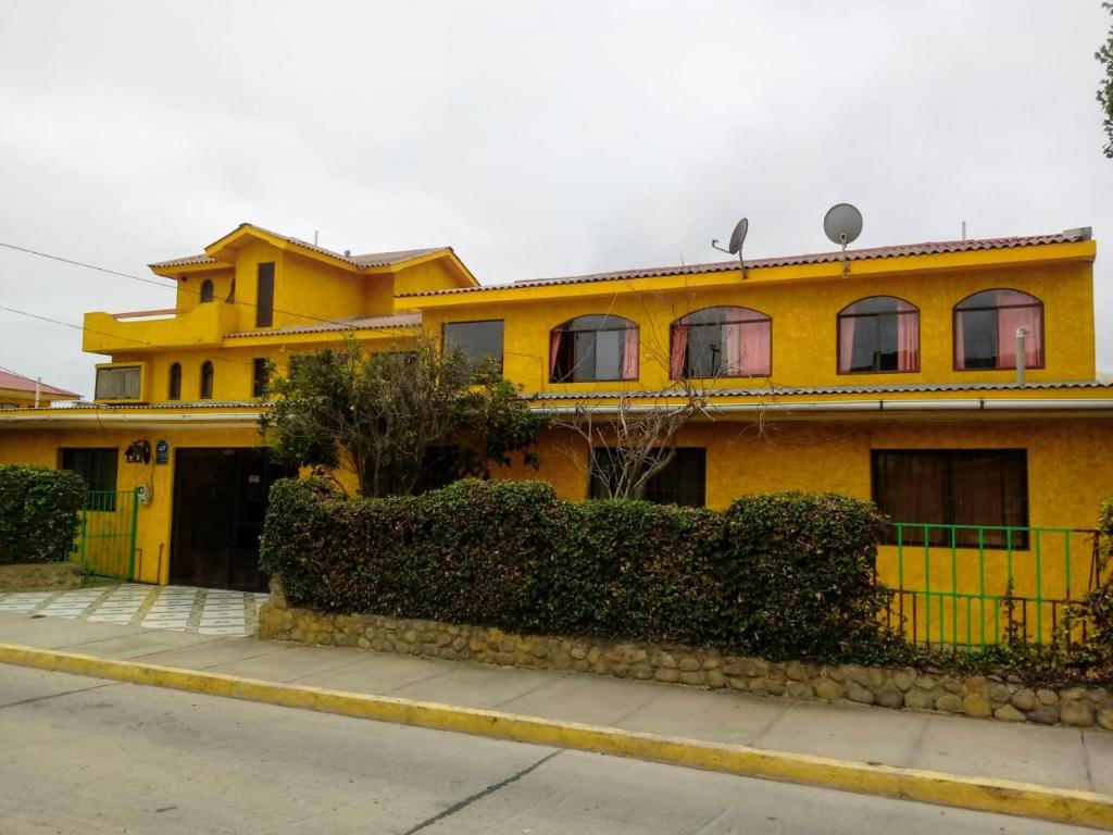 une maison jaune avec une clôture devant elle dans l'établissement Hotel San Juan, à Coquimbo