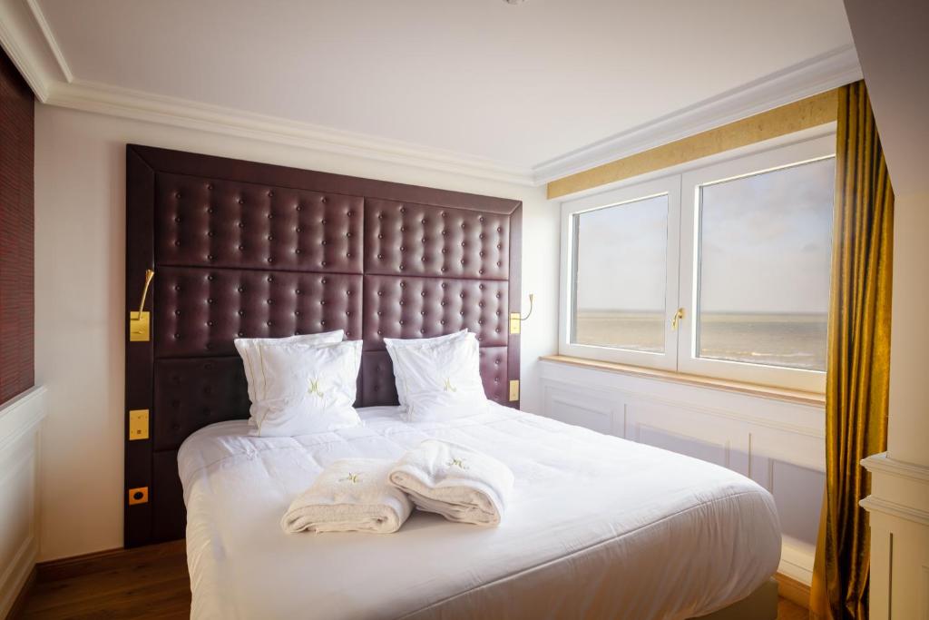 a bedroom with a large bed with towels on it at Hôtel Merveilleux Côté Mer in Dunkerque