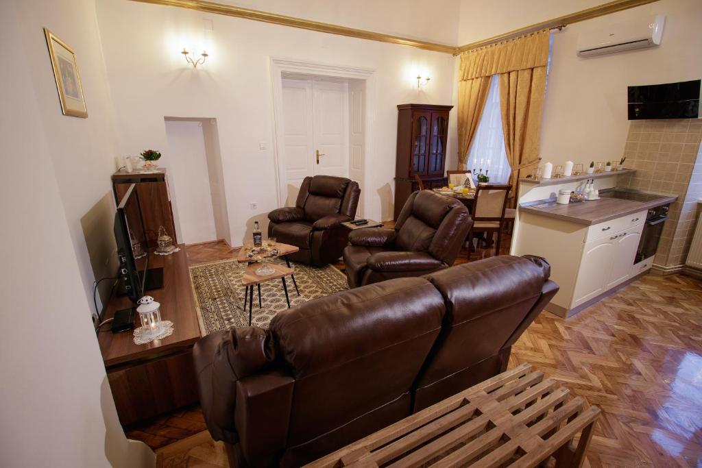 una sala de estar con un sofá de cuero marrón y sillas en Little Vienna Gold Apartment, en Varaždin