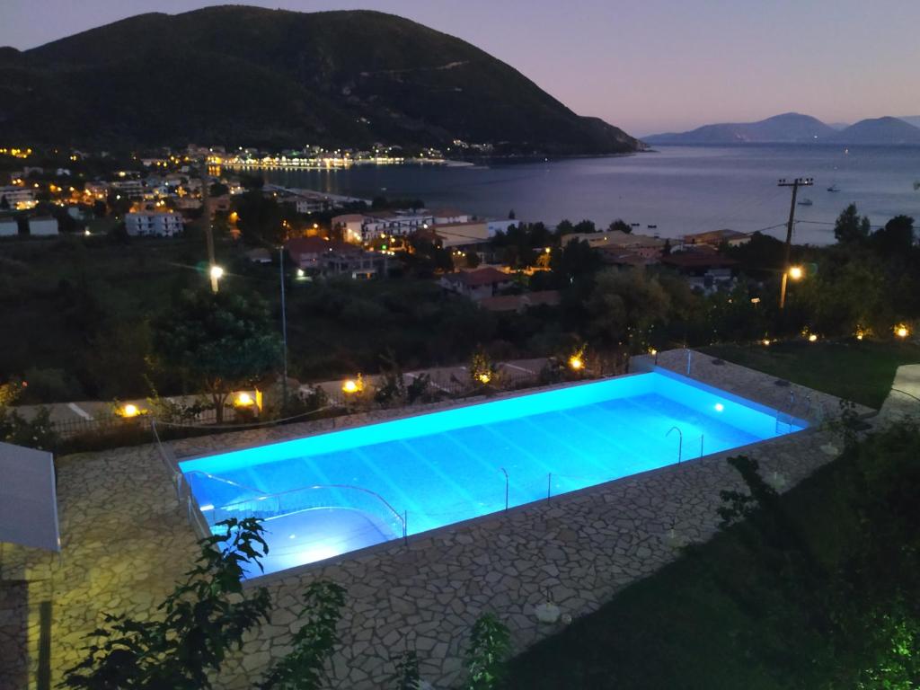 una piscina notturna con vista sulla città di Katerina Lefkada a Vassiliki