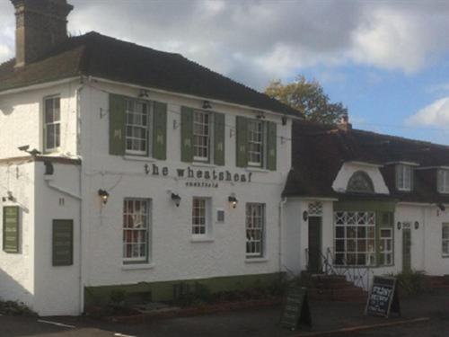 un edificio blanco con un cartel. en The Wheatsheaf Inn, en Cuckfield