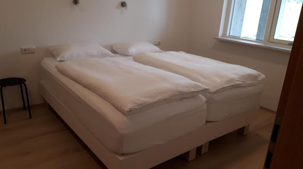 un letto bianco in una stanza con finestra di Skipalaekur Farm Apartments a Egilsstadir