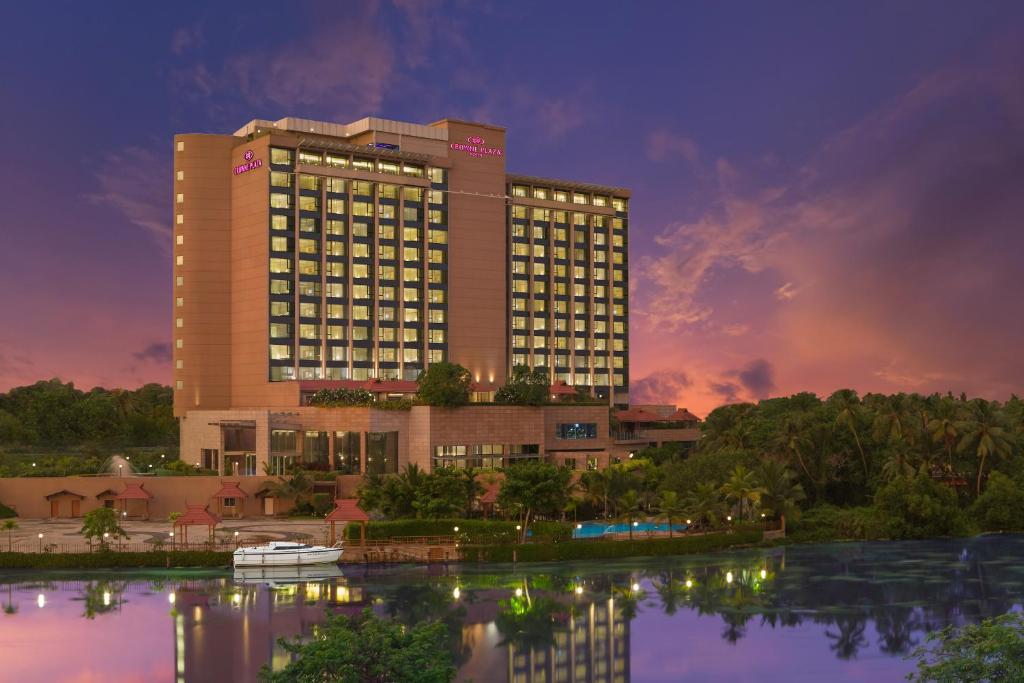 een hotelgebouw met een reflectie in het water bij Crowne Plaza Kochi, an IHG Hotel in Cochin