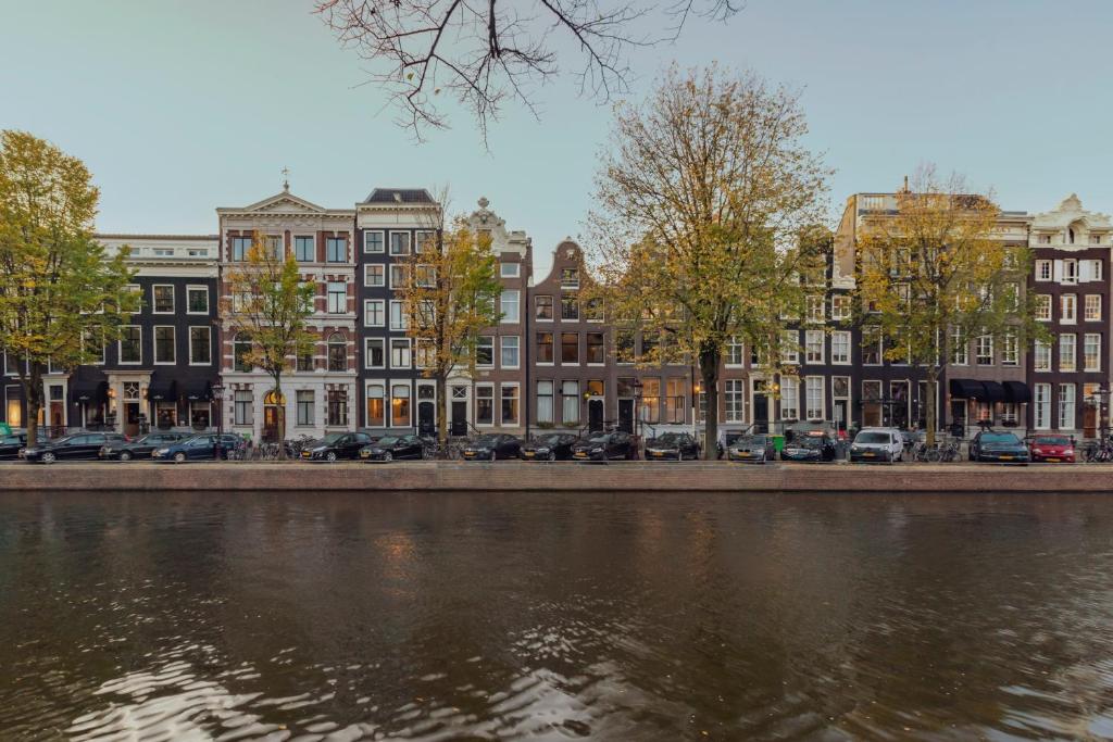 The Pavilions Amsterdam, The Toren في أمستردام: صف مباني بجانب نهر فيه سيارات