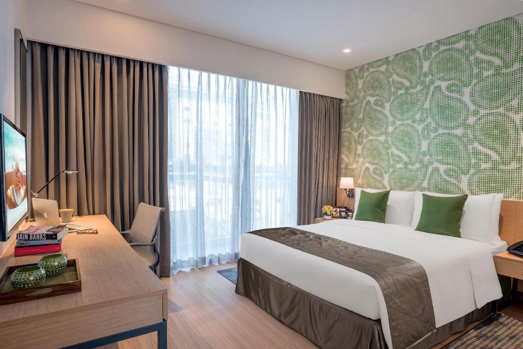 a hotel room with a large bed and a desk at Citadines OMR Chennai in Chennai