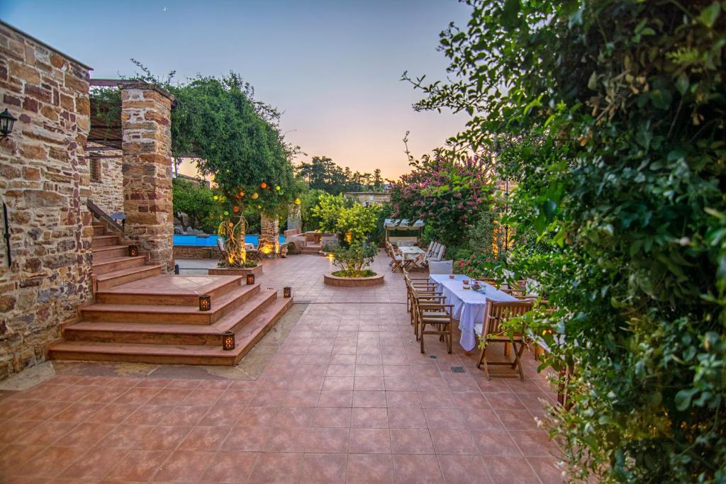 un patio extérieur avec des tables et des chaises ainsi qu'une piscine dans l'établissement Mouzaliko Guesthouse Mansion, à Kambos