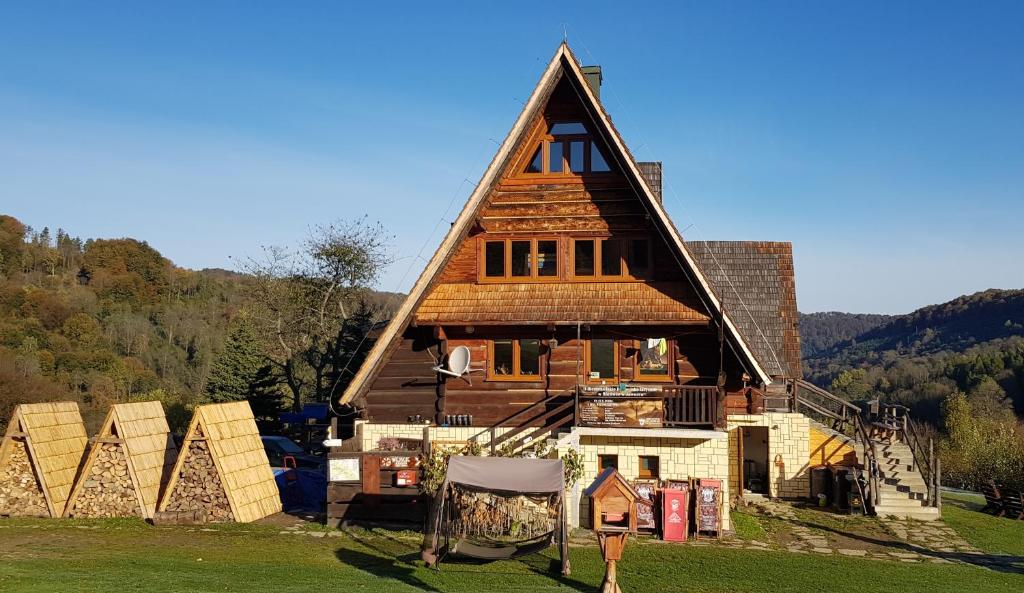 una grande casa con tetto di paglia su un campo di Bacówka PTTK Jaworzec a Wetlina