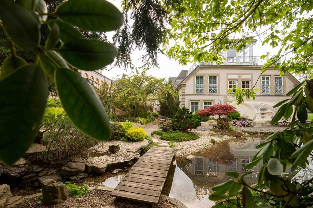 einen Garten mit einer Holzbrücke vor einem Haus in der Unterkunft Garten-Hotel Ochensberger in Sankt Ruprecht an der Raab