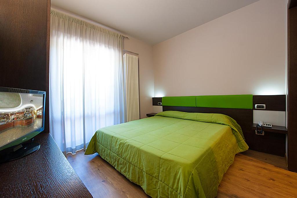 a bedroom with a green bed and a flat screen tv at Hotel Plestina Ristorante Pizzeria in Foligno