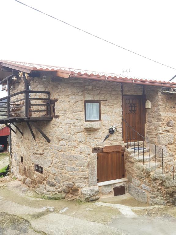 a stone house with a wooden door and a balcony at A Paragűeria in Sas de Penelas