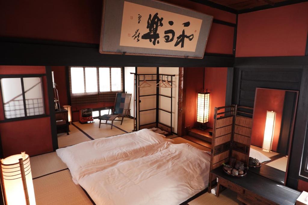 ein Schlafzimmer mit einem Bett in einem Zimmer mit einem Schild in der Unterkunft 一棟貸ゲストハウス 傾㐂屋 Kabukiya in Hiroshima