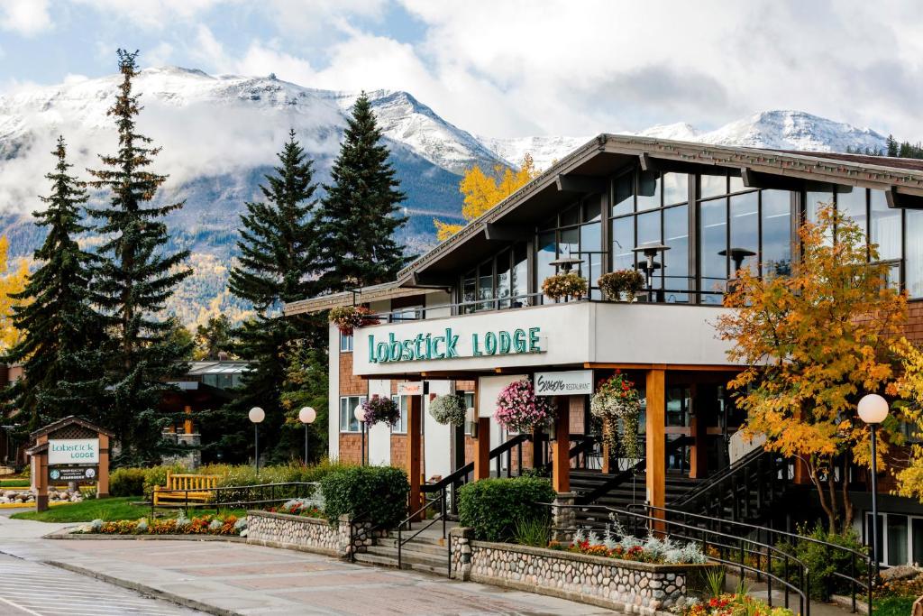 un edificio con un cartel que lee lodge británico con montañas en el fondo en Lobstick Lodge, en Jasper