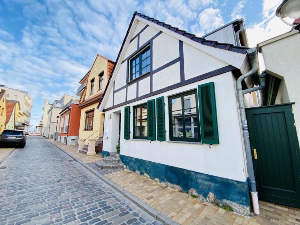 une maison blanche et verte dans une rue pavée dans l'établissement Ferienhaus Maria, à Warnemünde