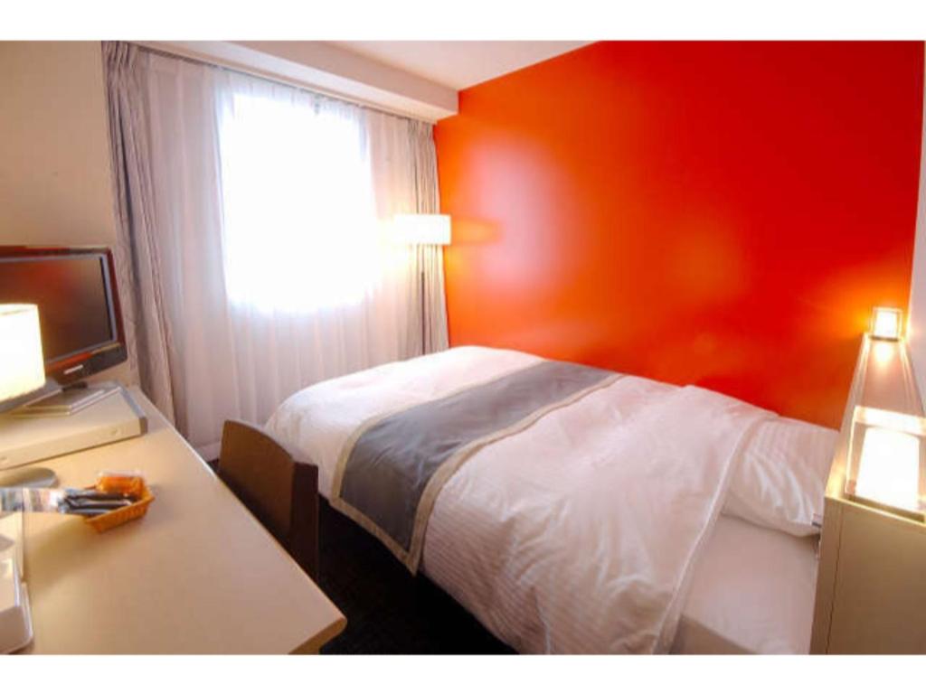 um quarto de hotel com uma cama, uma secretária e uma janela em Hotel Frontier Iwaki / Vacation STAY 79266 em Iwaki