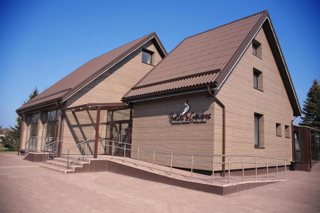 a large wooden building with a gambrel roof at Baltas gandras in Naisiai