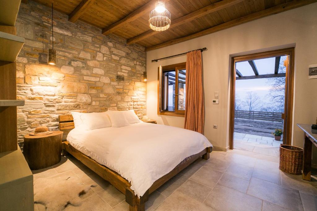 - une chambre avec un lit et un mur en pierre dans l'établissement Karaiskos Agritourism Farm, à Portariá