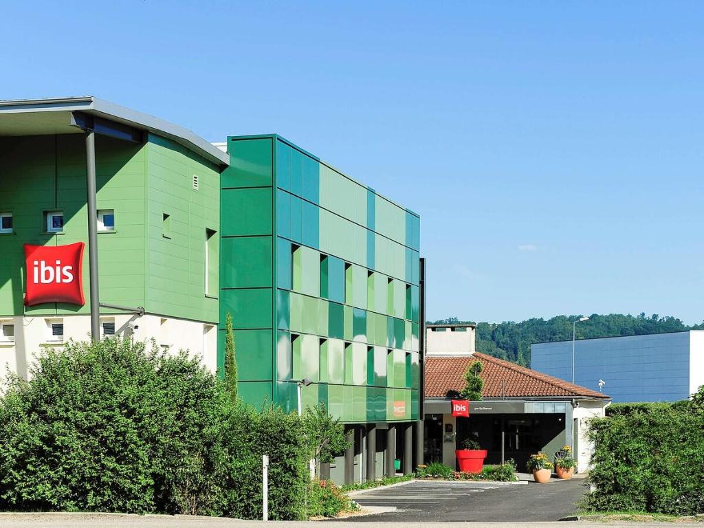 un edificio de cristal verde frente a un edificio en ibis Lyon Est Beynost, en Beynost