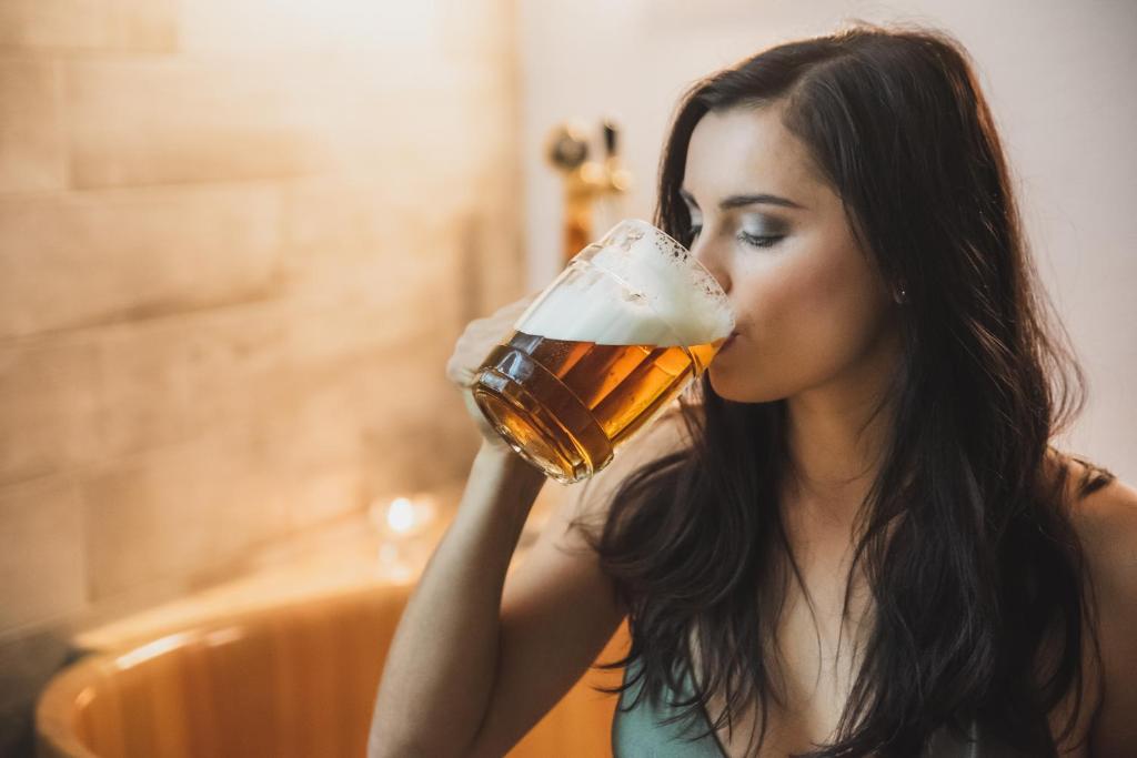 een vrouw die een glas bier drinkt bij Valašský Hotel a Pivní lázně OGAR in Luhačovice