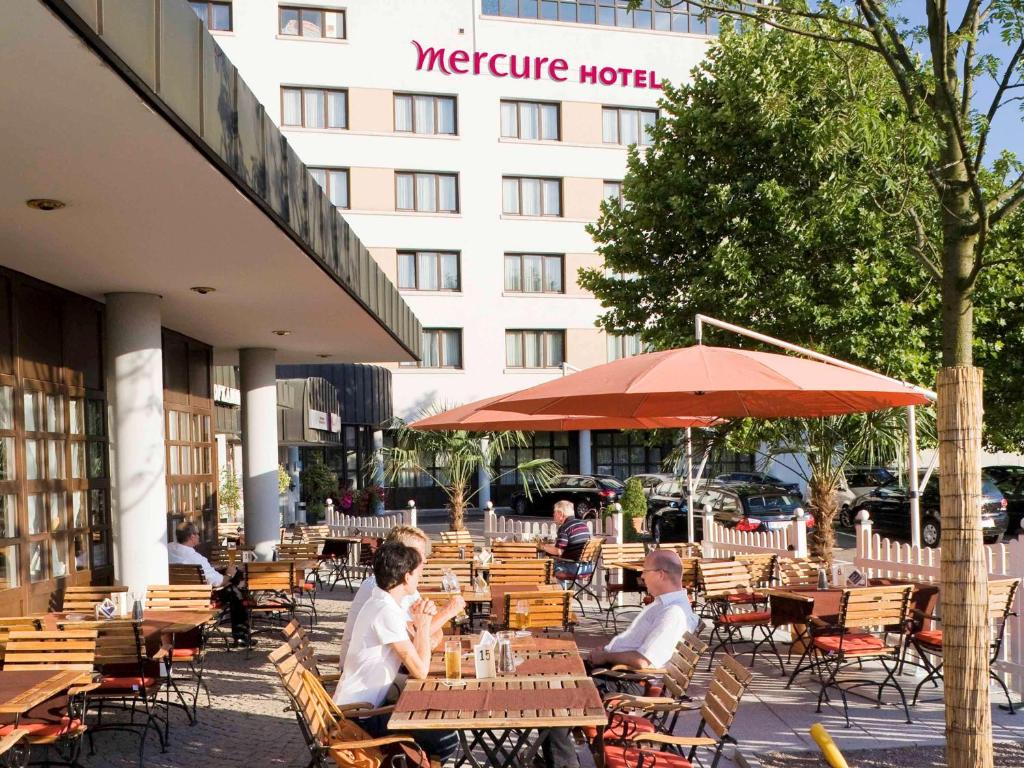 grupa ludzi siedzących przy stolikach przed hotelem w obiekcie Mercure Hotel am Messeplatz Offenburg w mieście Offenburg