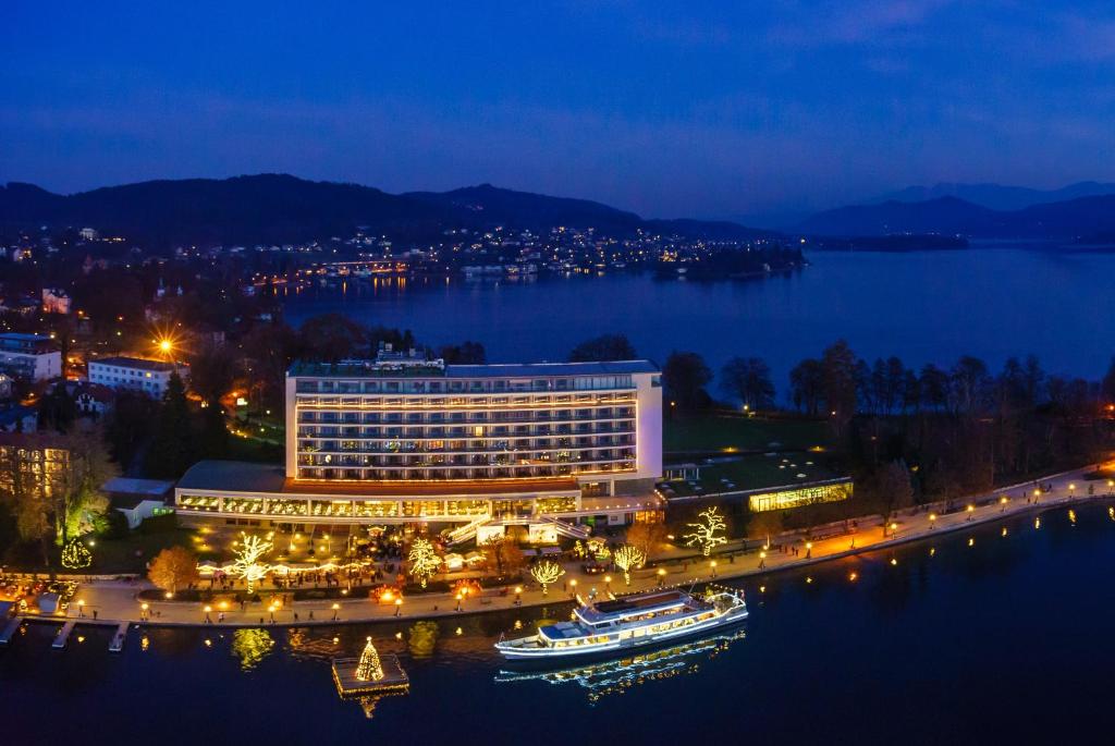 un hotel sulla riva di un lago di notte di Parkhotel Pörtschach - Das Hotelresort mit Insellage am Wörthersee a Pörtschach am Wörthersee