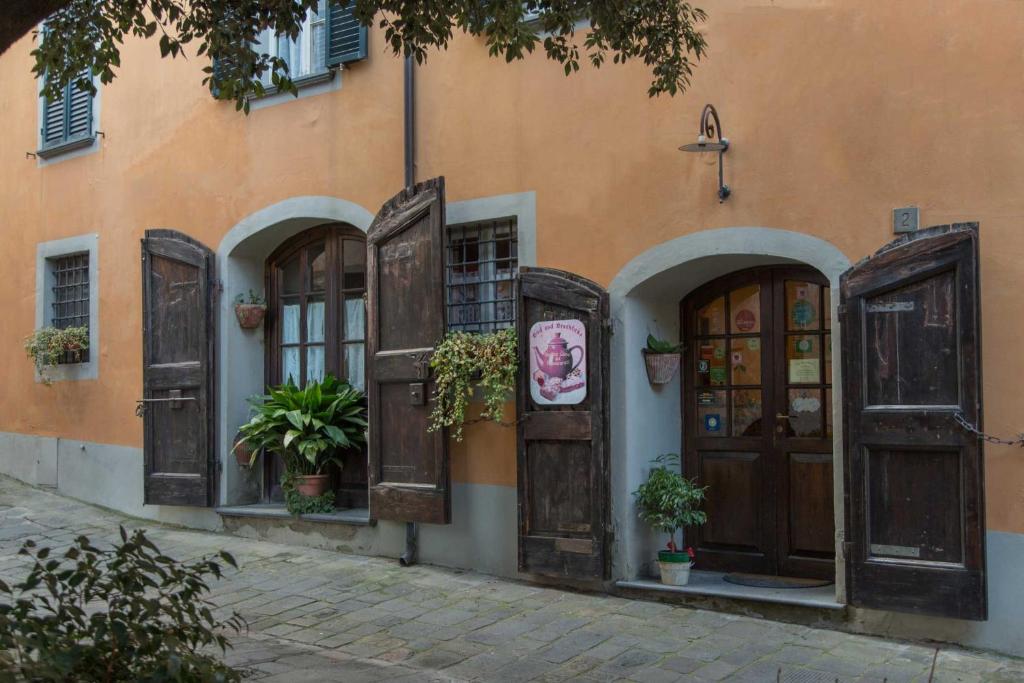 un edificio arancione con porte in legno e piante in vaso di Antica Casa Dei Rassicurati a Montecarlo