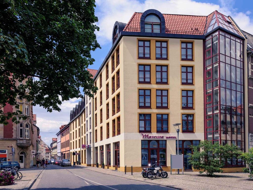 um edifício alto com um telhado vermelho numa rua em Mercure Hotel Erfurt Altstadt em Erfurt