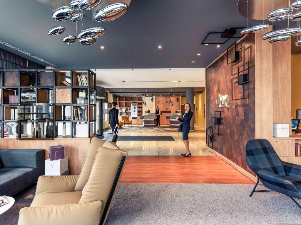 a woman standing in a living room with a couch at Mercure Hotel Mannheim am Rathaus in Mannheim