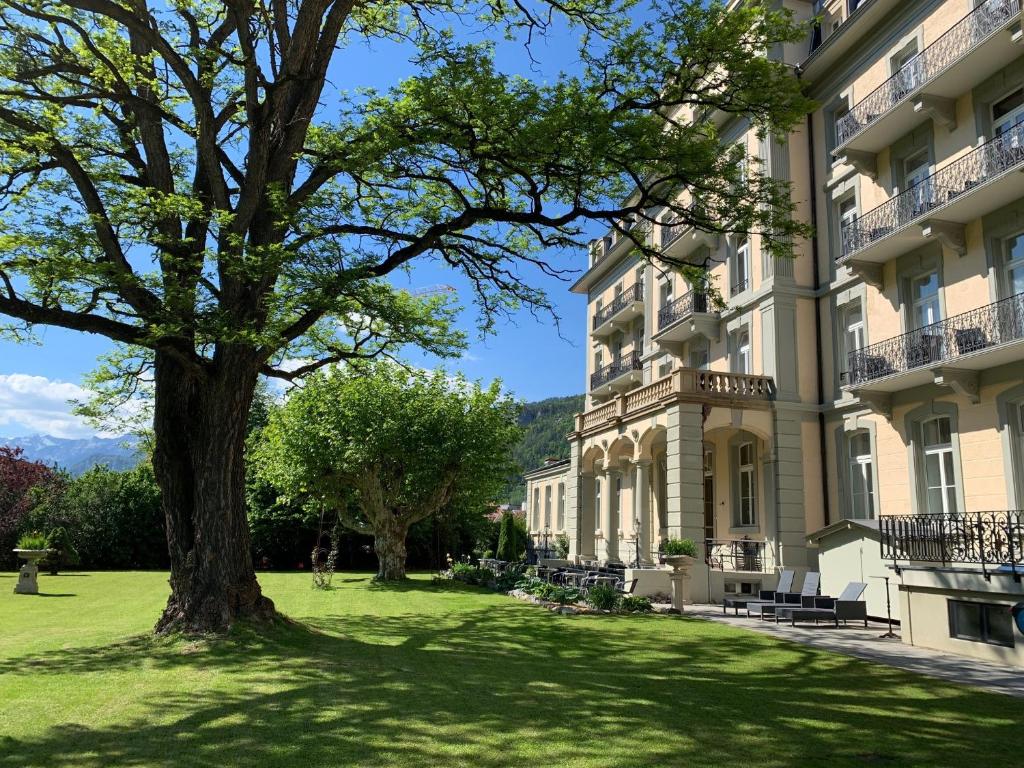 een groot gebouw met een boom ervoor bij Parkhotel du Sauvage in Meiringen