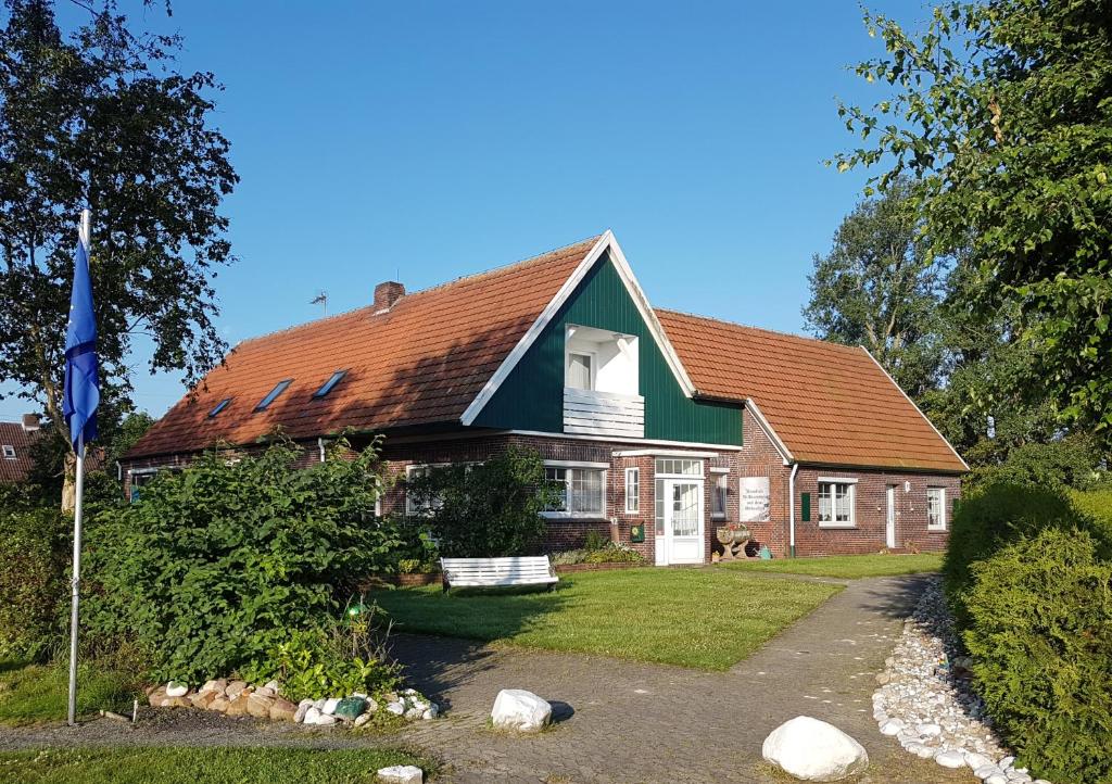 uma casa com telhado vermelho e verde em Birkenhof Neuharlingersiel em Neuharlingersiel