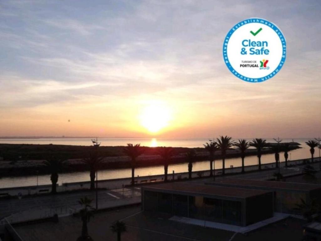 een zonsondergang over de oceaan met een bord dat zegt schoon en veilig bij Hotel Mar Azul in Lagos